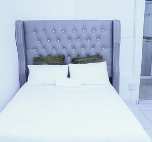 A bed with smooth white linen and white pillows